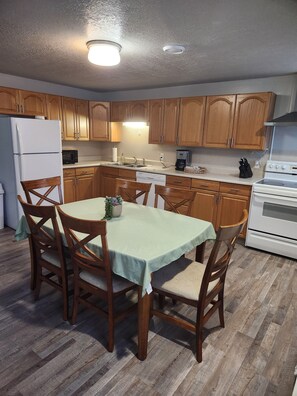 A compact kitchen with wooden cabinets, a white refrigerator, a microwave, a coffee maker, and a stove.