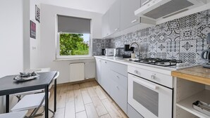 Una cocina moderna con armarios blancos, una estufa a gas y una ventana con vistas al follaje.
