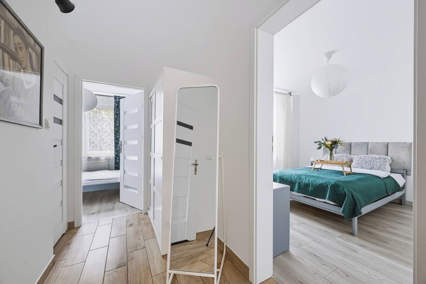 Et soveværelse med seng, sengebord og en hængende lampe.