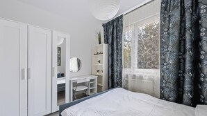 Un dormitorio con cama, escritorio, armario y ventana con cortinas.
