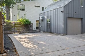 Eine Wohngarage mit Betonauffahrt, Holzzaun und einem Gebäudebau mit Garagentor.