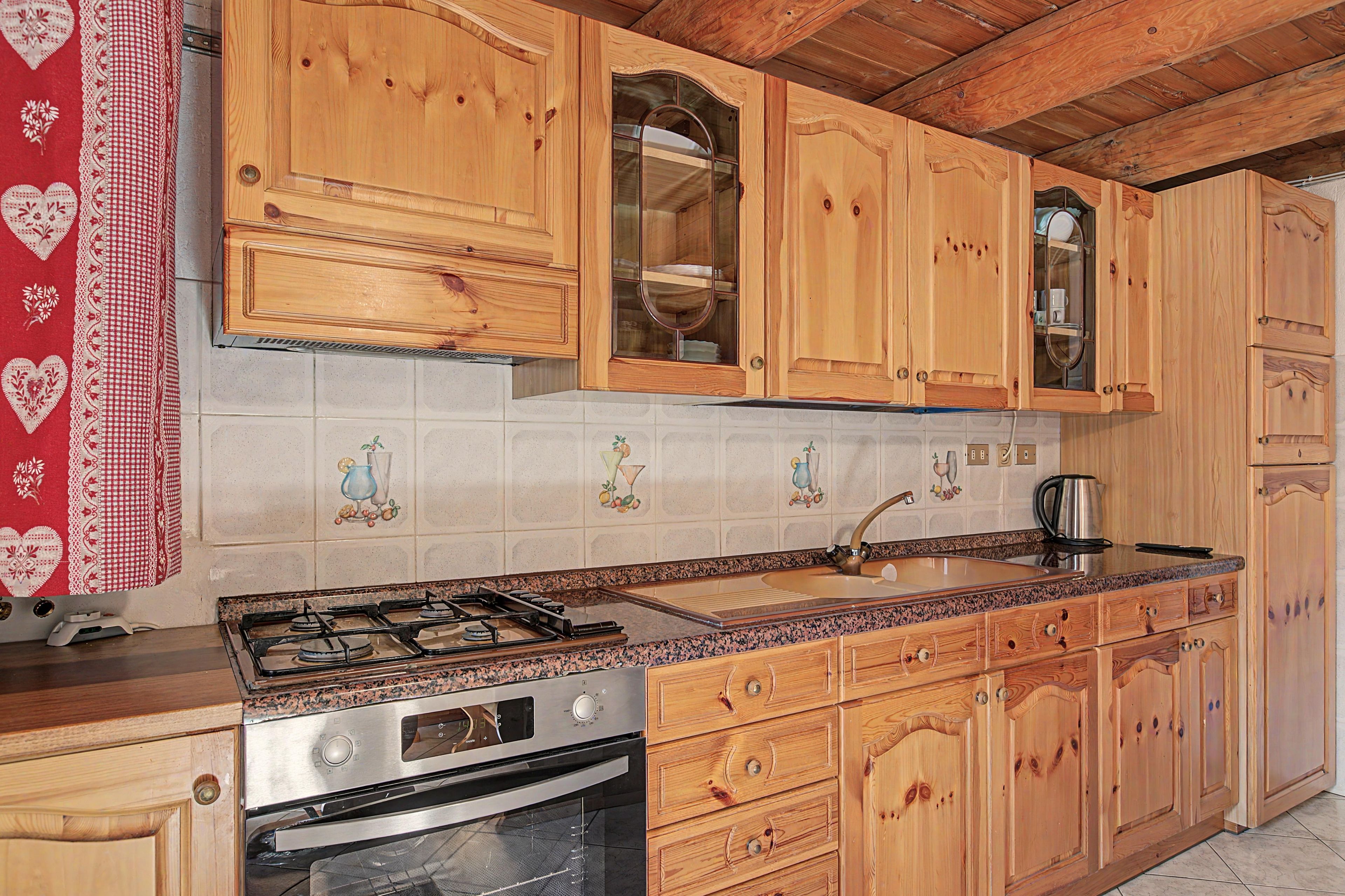 Une cuisine avec des meubles de rangement en bois, une cuisinière à gaz, un four et un évier.