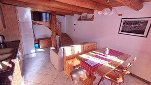 A rustic interior with a wooden dining table, chairs, a staircase, and a kitchen area. - Chalet 'Lo Pailler De Nonno' with Mountain View, Shared Garden, and Wi-Fi (Maisonasse)