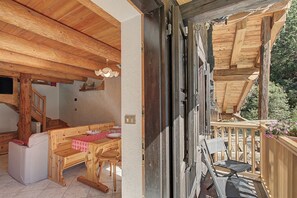 Een houten interieur met een eettafel gedekt voor twee personen, een bank en een stoel.