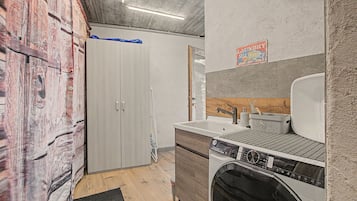 Ein Waschraum mit Waschmaschine, Spüle und einem Holzschrank.