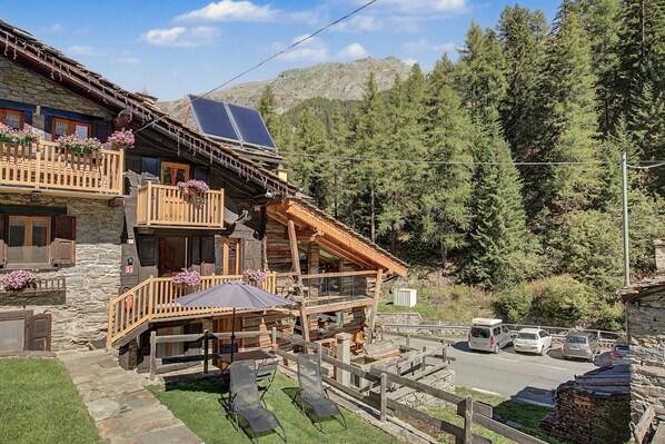 A log cabin with a balcony, outdoor seating, and solar panels.