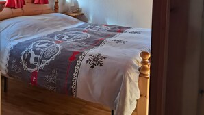A bedroom with a wooden ceiling, a bed with a patterned bedspread, and red curtains. - Chalet 'Lo Pailler De Nonno' with Mountain View, Shared Garden, and Wi-Fi (Maisonasse)