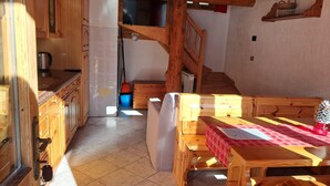 Un interior de fusta amb cuina, zona de menjador i una escala.