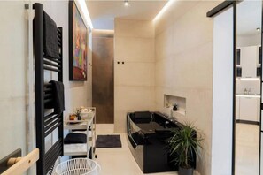 A modern bathroom with a black bathtub, a white sink, and a shower area.