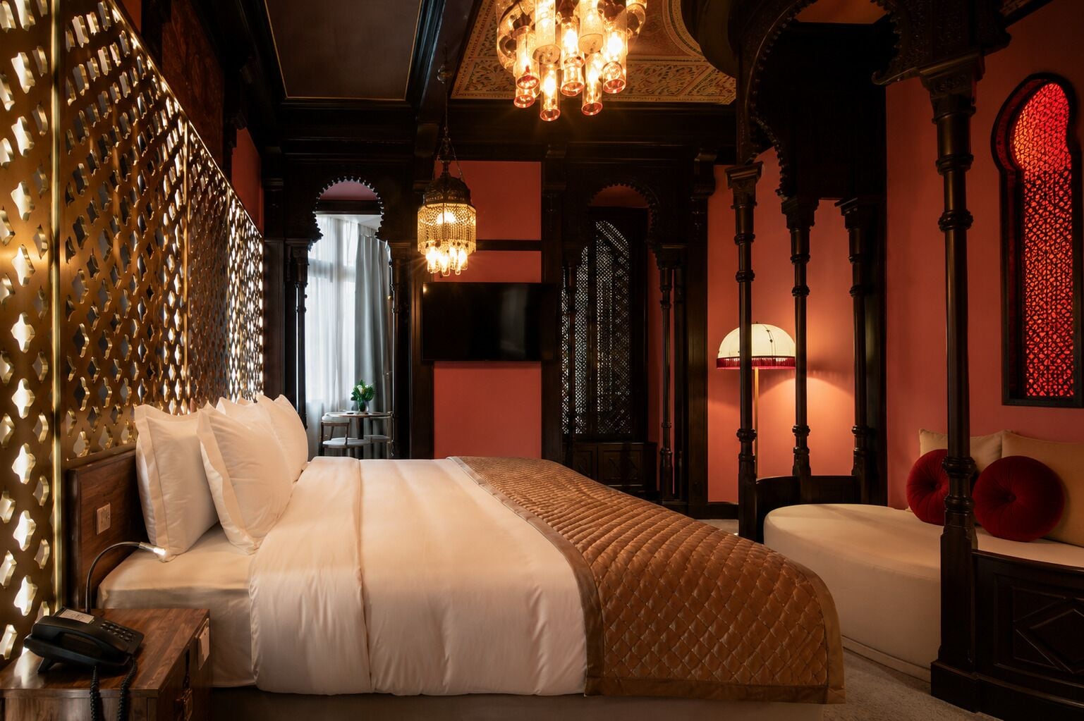 Een hotelkamer met een groot bed, een kroonluchter en versierde architectuur.