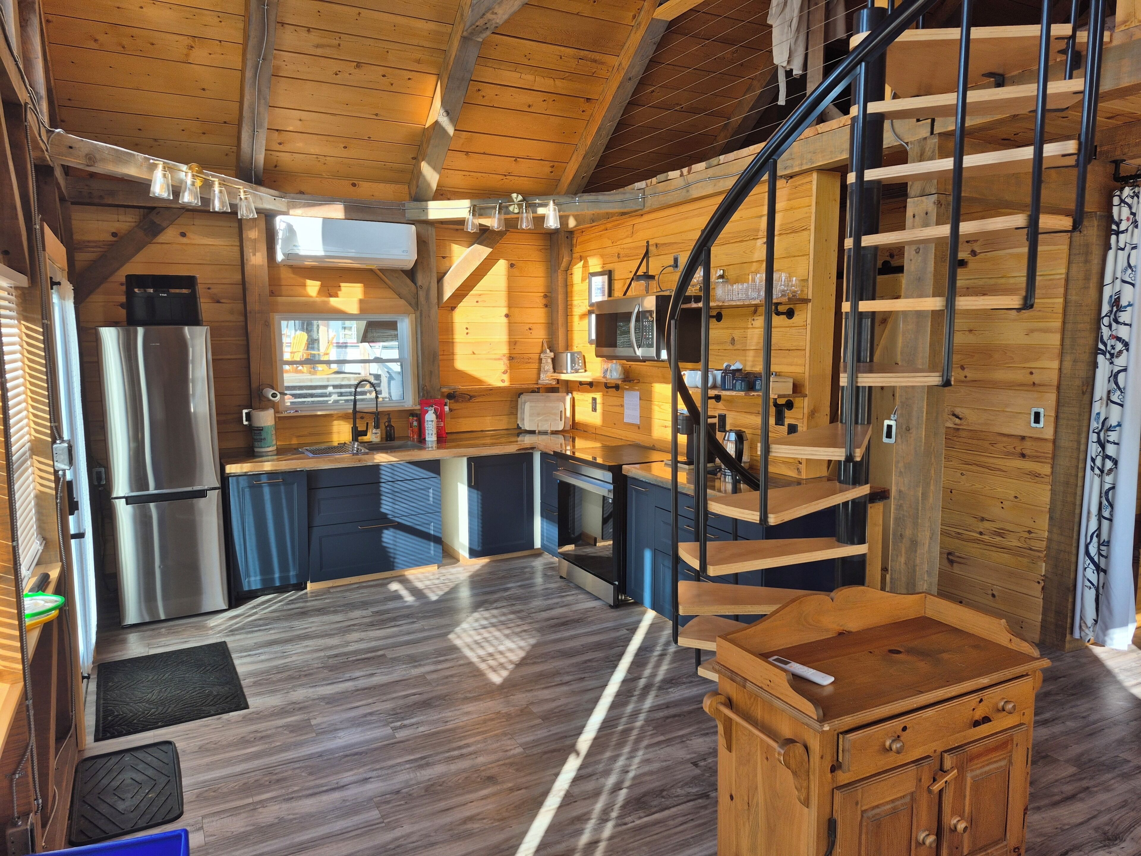 Une cuisine compacte dotée d’appareils électroménagers modernes, d’un intérieur en bois et d’un escalier en colimaçon.