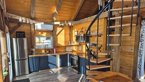Una cocina compacta con electrodomésticos modernos, detalles de madera y una escalera en espiral.