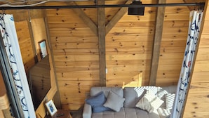 Una habitación acogedora con un sofá gris, un sillón azul y suelo de madera.