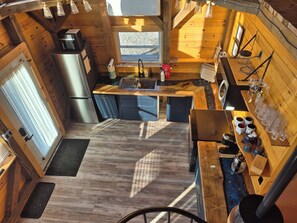 Eine kleine Küche mit einem Edelstahl-Kühlschrank, Holzschränken und einem Fenster für natürliches Licht.