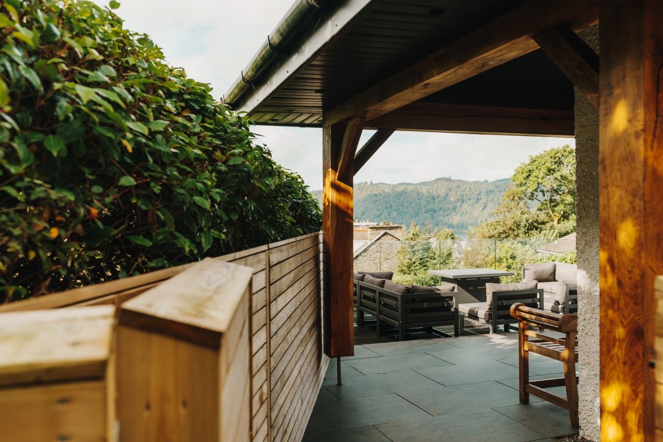 En udendørs terrasse med træmøbler og udsigt over det omkringliggende landskab.