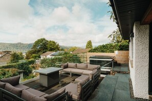 Eine Außenpatio mit einer Sofagruppe, einem Tisch und einem Whirlpool.