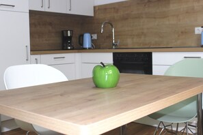 A modern kitchen with white cabinets, a wooden countertop, a green apple, a coffee maker, and a kettle. - Apartment Spiegelkurve (Adenau)