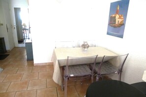 A dining area with a table and chairs, a small vase, and a framed picture on the wall. - Bright Apartment by the Ligurian sea (La croix-Valmer)