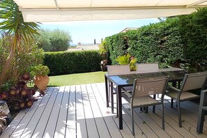 An outdoor patio with a table and chairs, surrounded by greenery and a hedge. - Bright Apartment by the Ligurian sea (La croix-Valmer)
