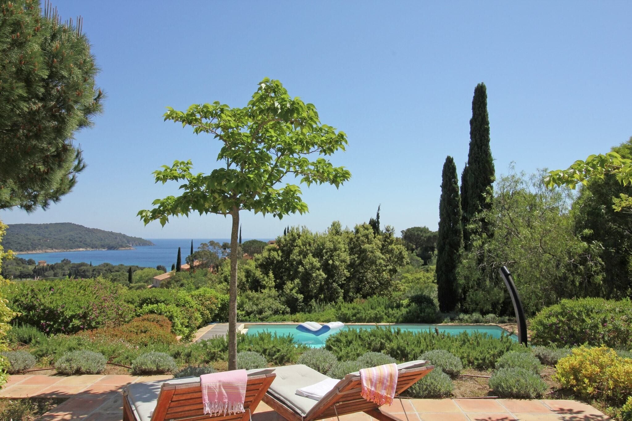 A poolside area with lounge chairs, a swimming pool, and a view of the sea.