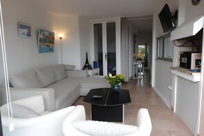 A modern living room with a sofa, a coffee table, and a TV mounted on the wall. - Bright Apartment by the Ligurian sea (La croix-Valmer)