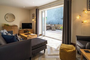 Ein modernes Wohnzimmer mit einer Couch, einem Couchtisch, einem Fernseher und einem Essbereich mit Stühlen und einem Tisch.