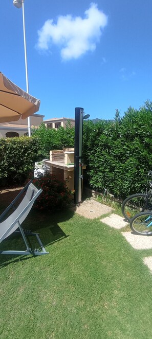 A patio area with a metal structure, a bicycle, and a well-maintained lawn. - Casa Luca in the Borghi of Villasimius  (Sardegna)