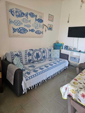 A room with a sofa, a television, and a wall with a fish pattern. - Casa Luca in the Borghi of Villasimius  (Sardegna)
