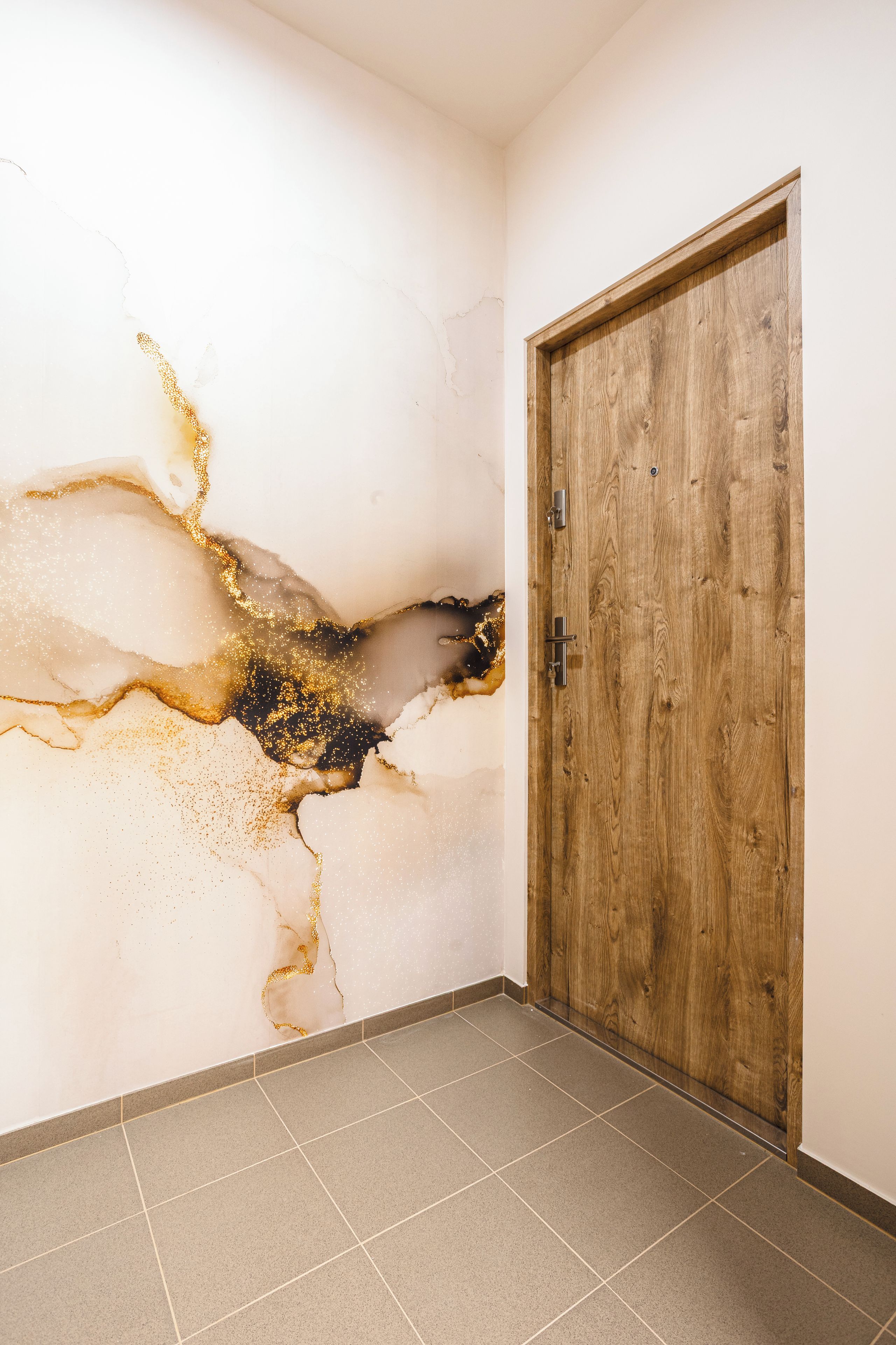 A hallway with a wooden door and a wall with a crack and gold specks.