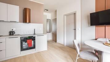 Una cocina moderna con armarios blancos, horno empotrado y campana extractora de acero inoxidable.