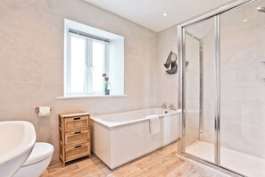 A modern bathroom with a freestanding bathtub, a glass-enclosed shower, and a window with a view. - Hillberry Cottage (Carnforth)