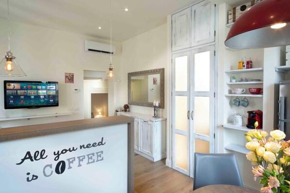 A kitchen with a wooden countertop, a wall-mounted TV, and a sign that reads 'All you need is COFFEE'. - Vrbo Property (Firenze)