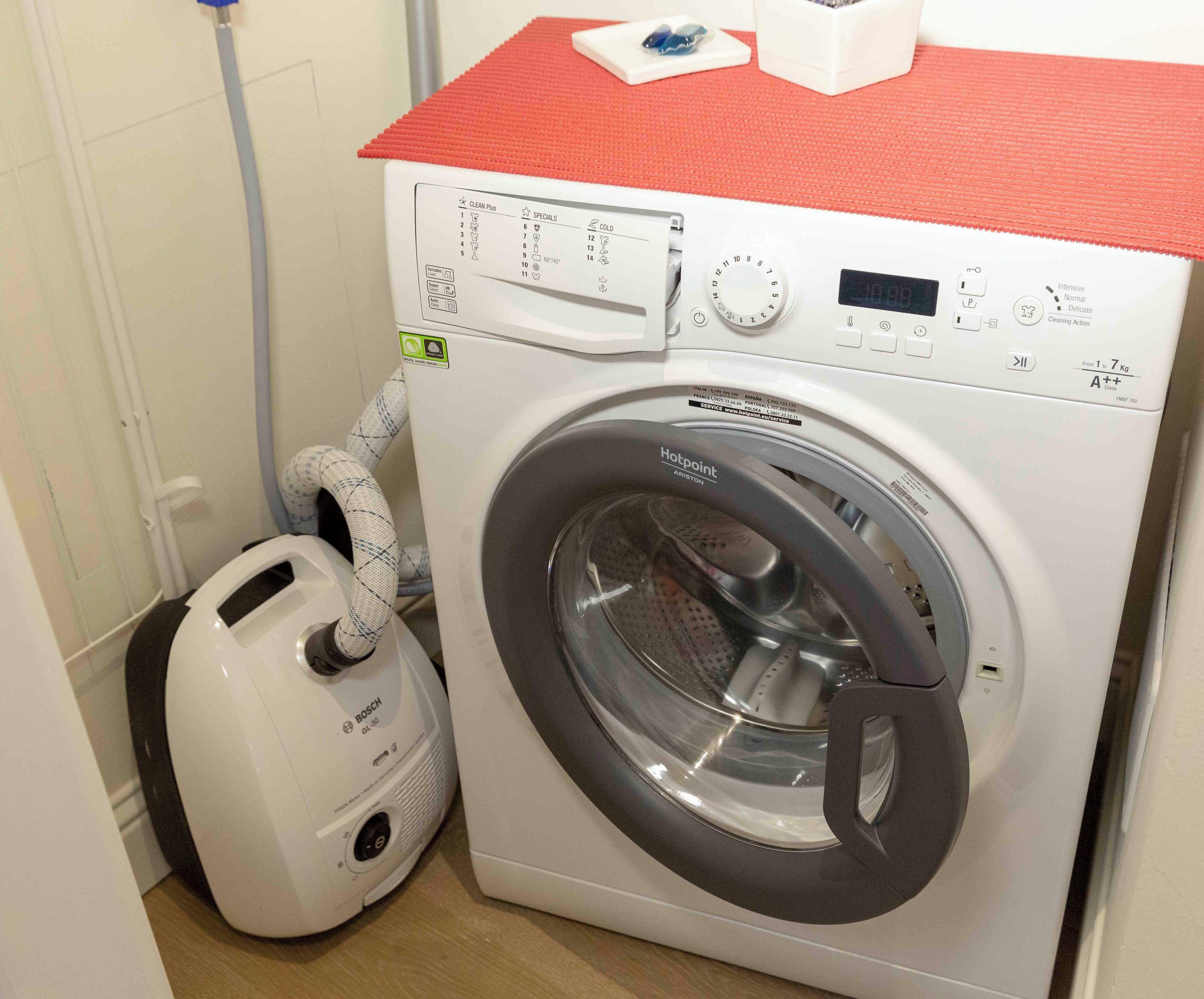 A front-loading washing machine with a digital display, control panel, and a red top.