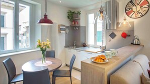 Een moderne keuken met een eethoek, een klok aan de muur en uitzicht op de straat.