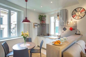 A modern kitchen with a dining area, a clock on the wall, and a view of the street outside. - Vrbo Property (Firenze)