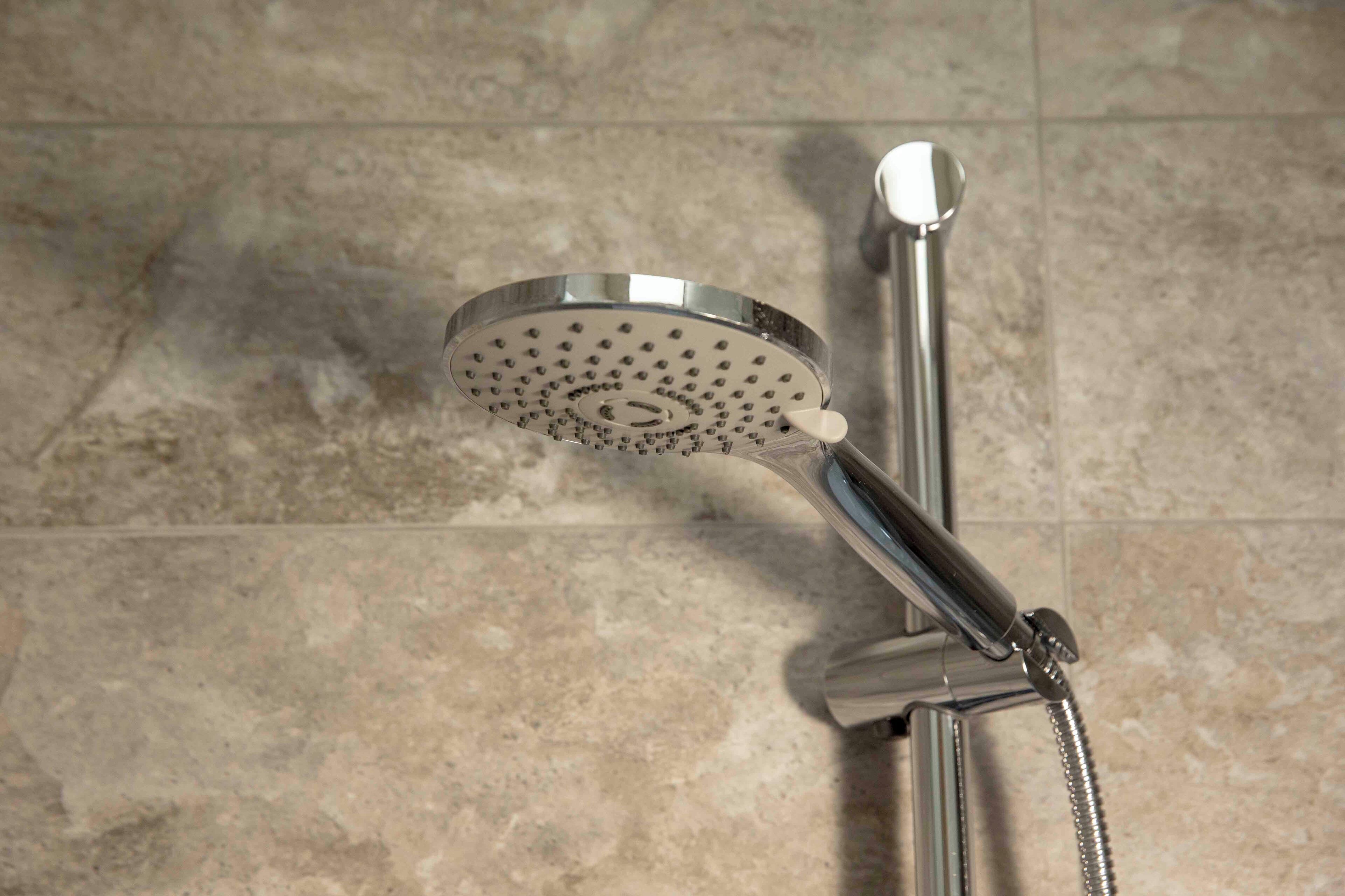 A showerhead with a circular, perforated design, attached to a chrome fixture.