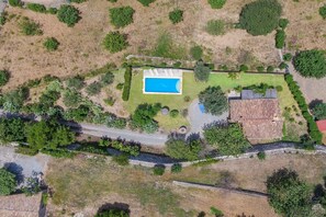 Eine Luftaufnahme eines Grundstücks mit Schwimmbad, gepflasterter Auffahrt und Steinmauer.