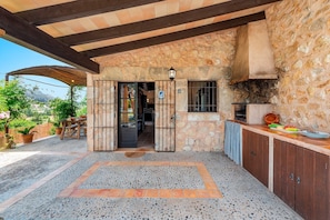 Ein Steinhaus mit einer überdachten Terrasse, einer Küchenzeile und Blick auf die umliegende Landschaft.