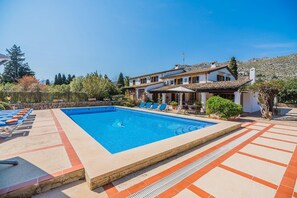 A rectangular swimming pool with a tiled deck area, surrounded by lounge chairs and a building with a tiled roof. - Charming Chalet for 8 in Pollensa (Pollensa / Pollença)