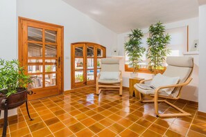 A room with a tiled floor, wooden doors, two chairs, a table, and potted plants. - Charming Chalet for 8 in Pollensa (Pollensa / Pollença)
