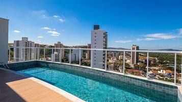 Piscina no terraço com vista para a cidade, rodeada por edifícios.