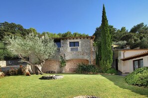 A stone building with a garden in front, a tall tree, and a clear blue sky. - Majorcan Mountain View Villa for 8 (Pollensa / Pollença)