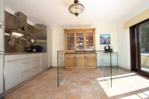 A kitchen with a central island, a stove, and a hanging pot rack. - Majorcan Mountain View Villa for 8 (Pollensa / Pollença)