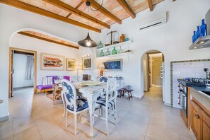 A spacious kitchen with a dining area, wooden beams, and various kitchen appliances. - Romantic Country Hideaway in Pollensa (Pollensa / Pollença)