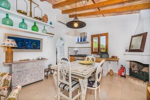 A rustic kitchen with a dining table, chairs, a hanging light fixture, and a fireplace. - Romantic Country Hideaway in Pollensa (Pollensa / Pollença)