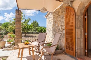 An outdoor seating area with a table and chairs, a stone wall, and a wooden door. - Romantic Country Hideaway in Pollensa (Pollensa / Pollença)