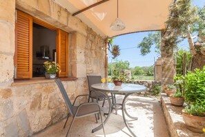 A stone building with a covered patio, a round table, and chairs. - Romantic Country Hideaway in Pollensa (Pollensa / Pollença)