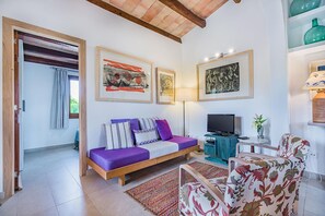 A living room with a sofa, a television, and artwork on the walls. - Romantic Country Hideaway in Pollensa (Pollensa / Pollença)