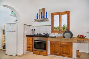 A compact kitchen with a stove, oven, and a window with wooden frames. - Romantic Country Hideaway in Pollensa (Pollensa / Pollença)