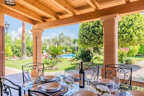 An outdoor dining area with a pool view, covered by a wooden pergola, and tables set for a meal. - CASETA DE LLOSETA Ref VP22 1 (Lloseta)